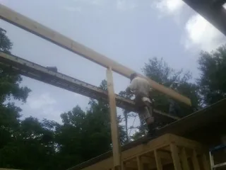 Carpenter setting a ridge beam over a new addition frame — Ice Dam Removal by Roofing Brothers in Pony