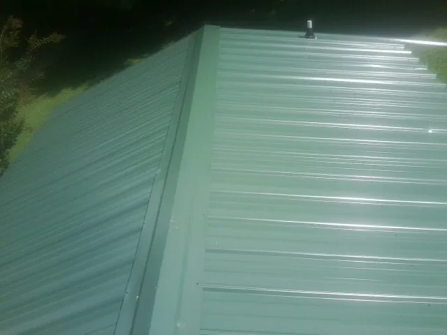 New green metal panels meeting at the ridge of a roof — Flat Roof Repair work by our crew in Pony