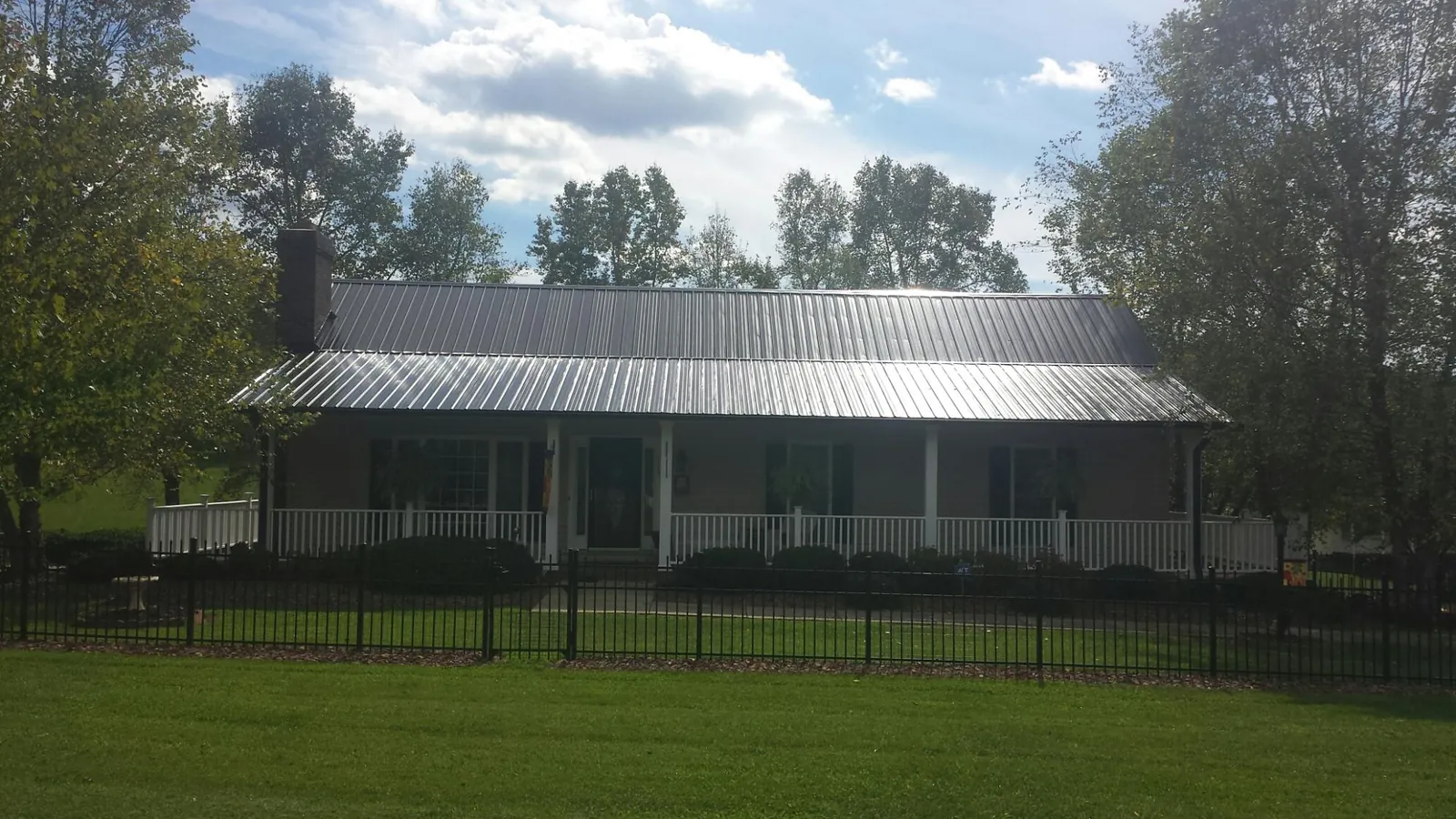 Gray metal roof on a brick ranch with a full width front porch — Gutter Guard Installation work by our crew in Pony