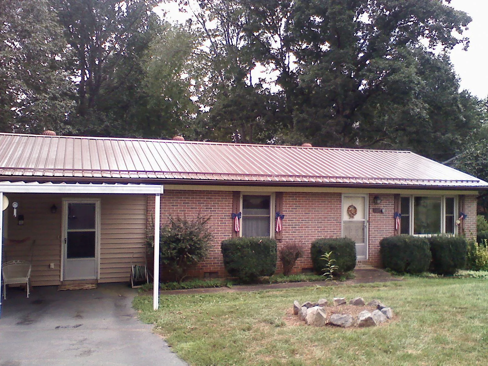 Bronze metal roof and carport on a brick ranch home — Roof Repair work by our crew in Pony
